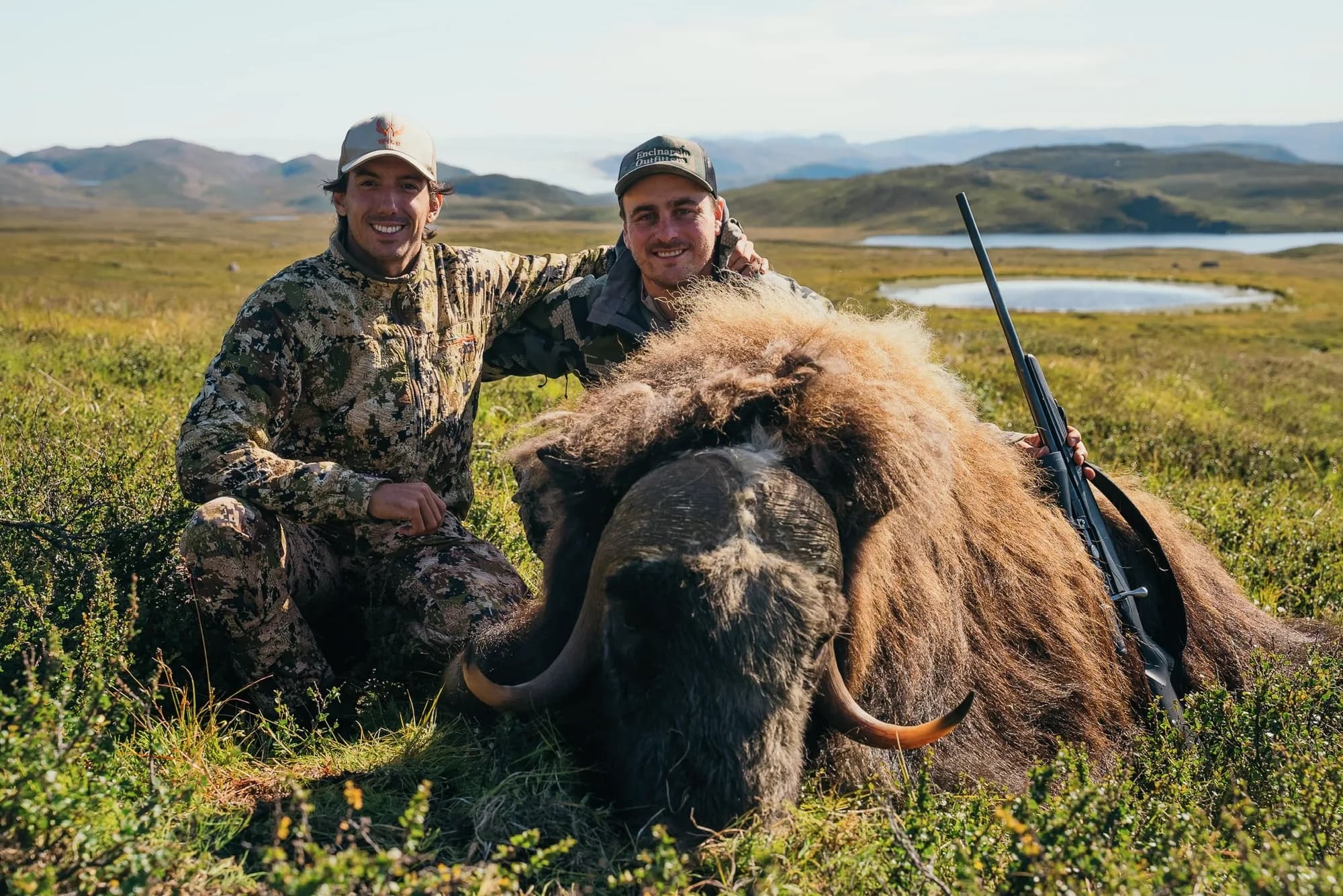 Two hunters with a muskox bull on the Greenland tundra