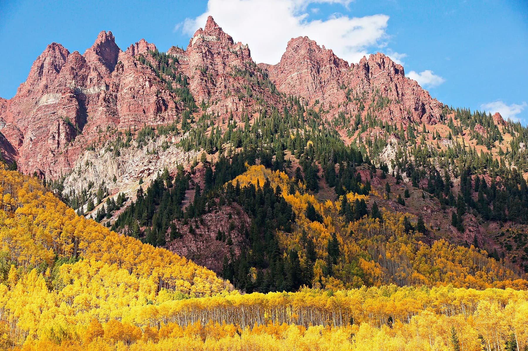 Red peaks above a hillside of turning aspen