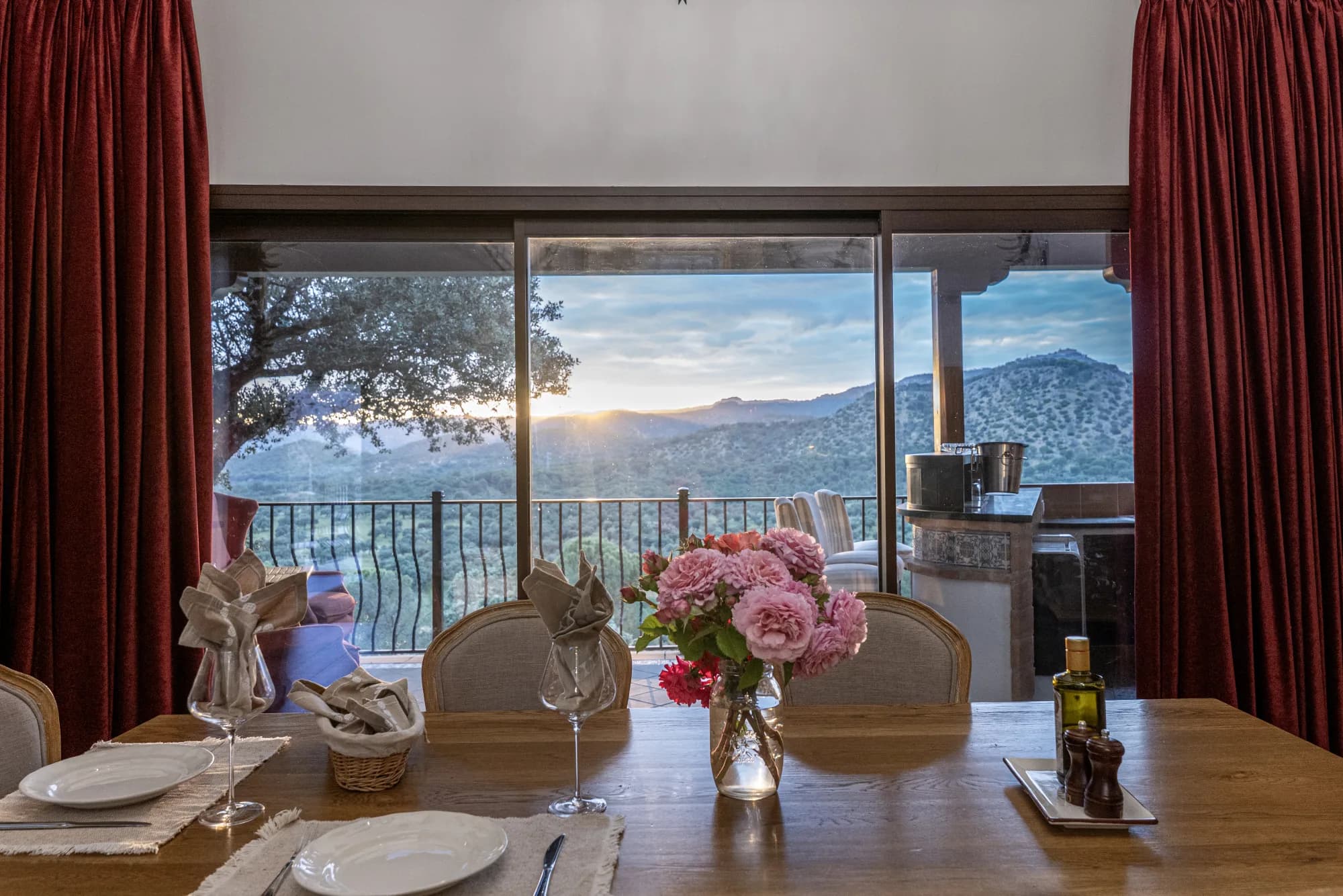The dining table laid at golden hour, the sierra through the window