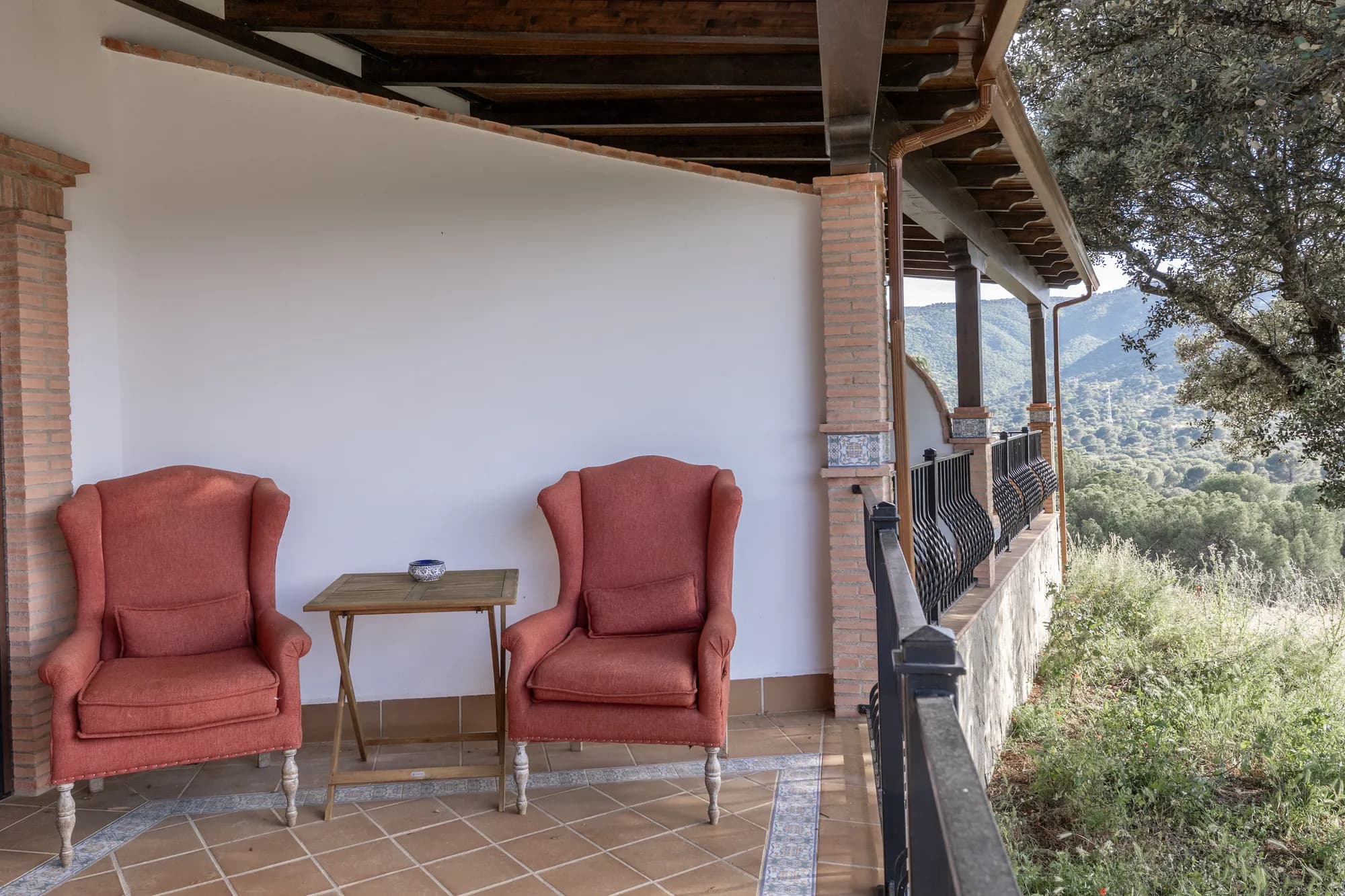 Two wingback chairs on the shaded terrace, facing the hunting country